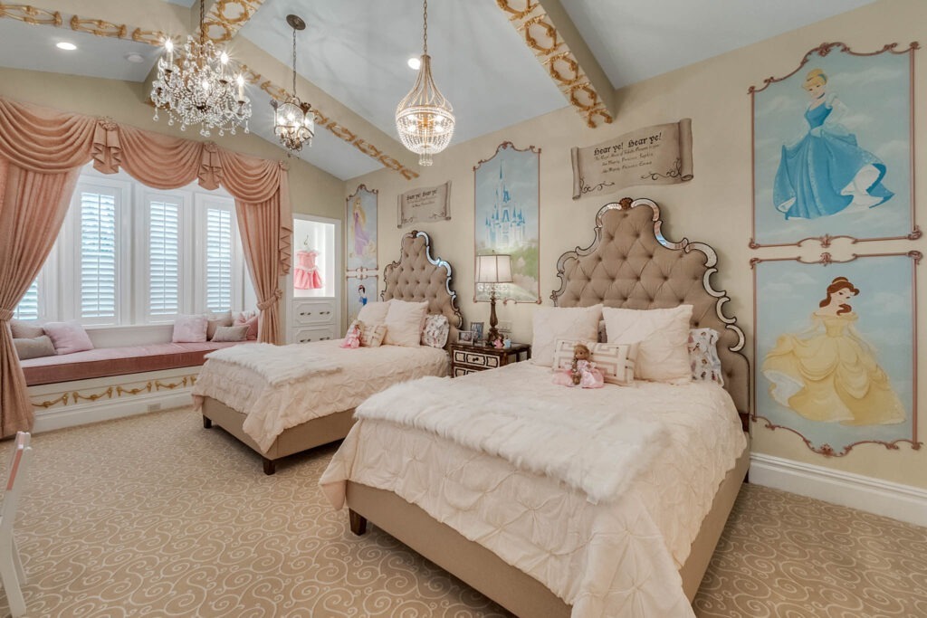 A children's bedroom with two upholstered beds, crystal chandeliers, and hand-painted fairytale murals on the walls.